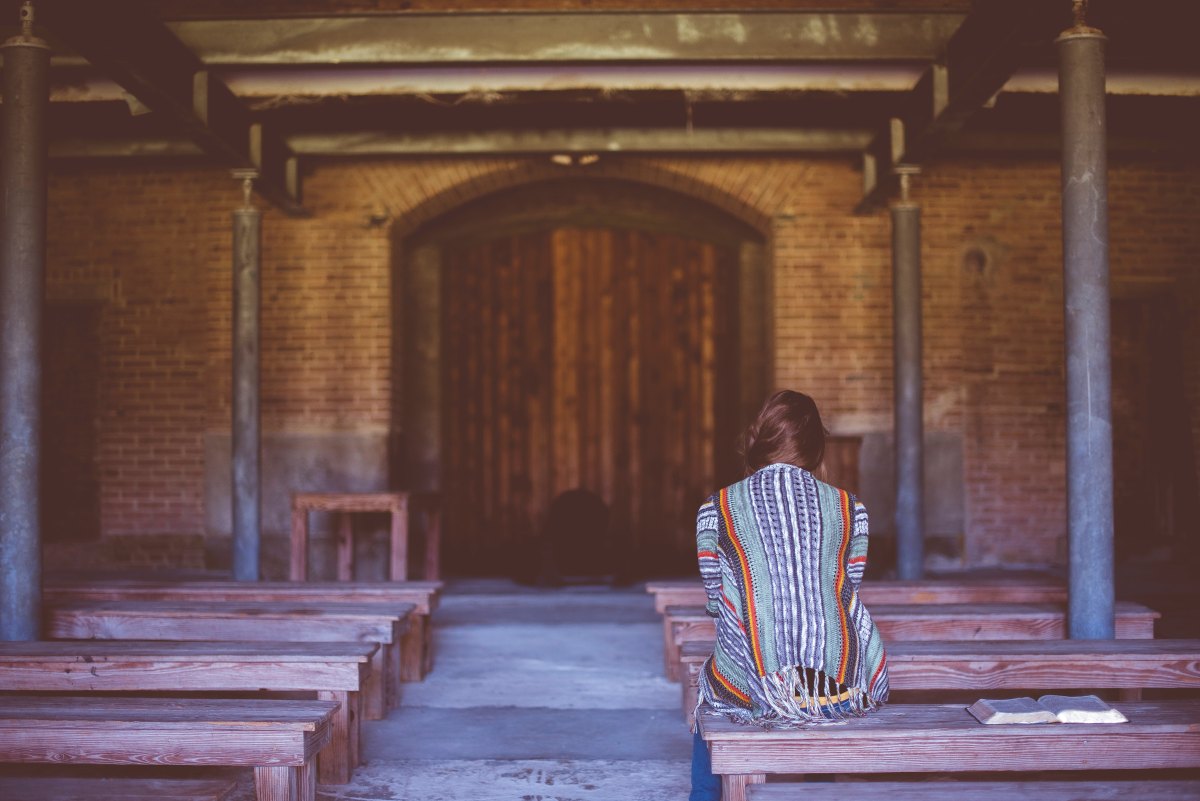 woman sitting on bench praying