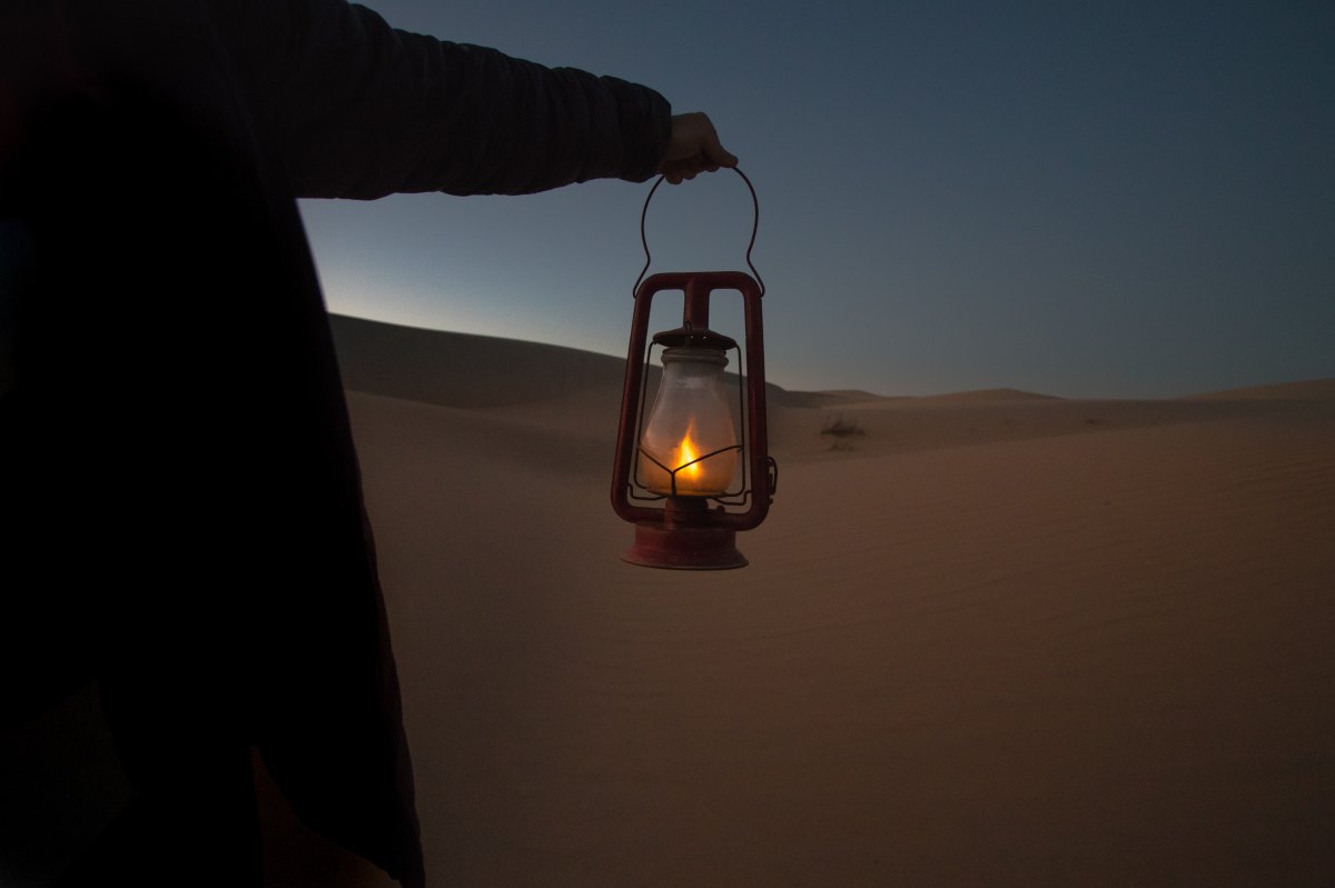 Person holding lantern in dark desert