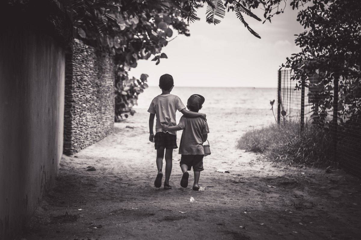 Two young boys walking away arm-in-arm
