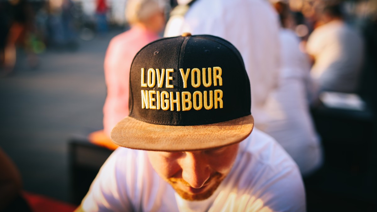 Young man wearing hat that says Love Your Neighbor.